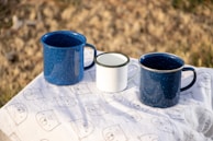 blue ceramic mugs on white table cloth