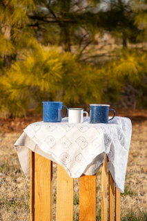 Three puzzle mugs arranged side by side on a wooden table, each showing a different abstract art piece.