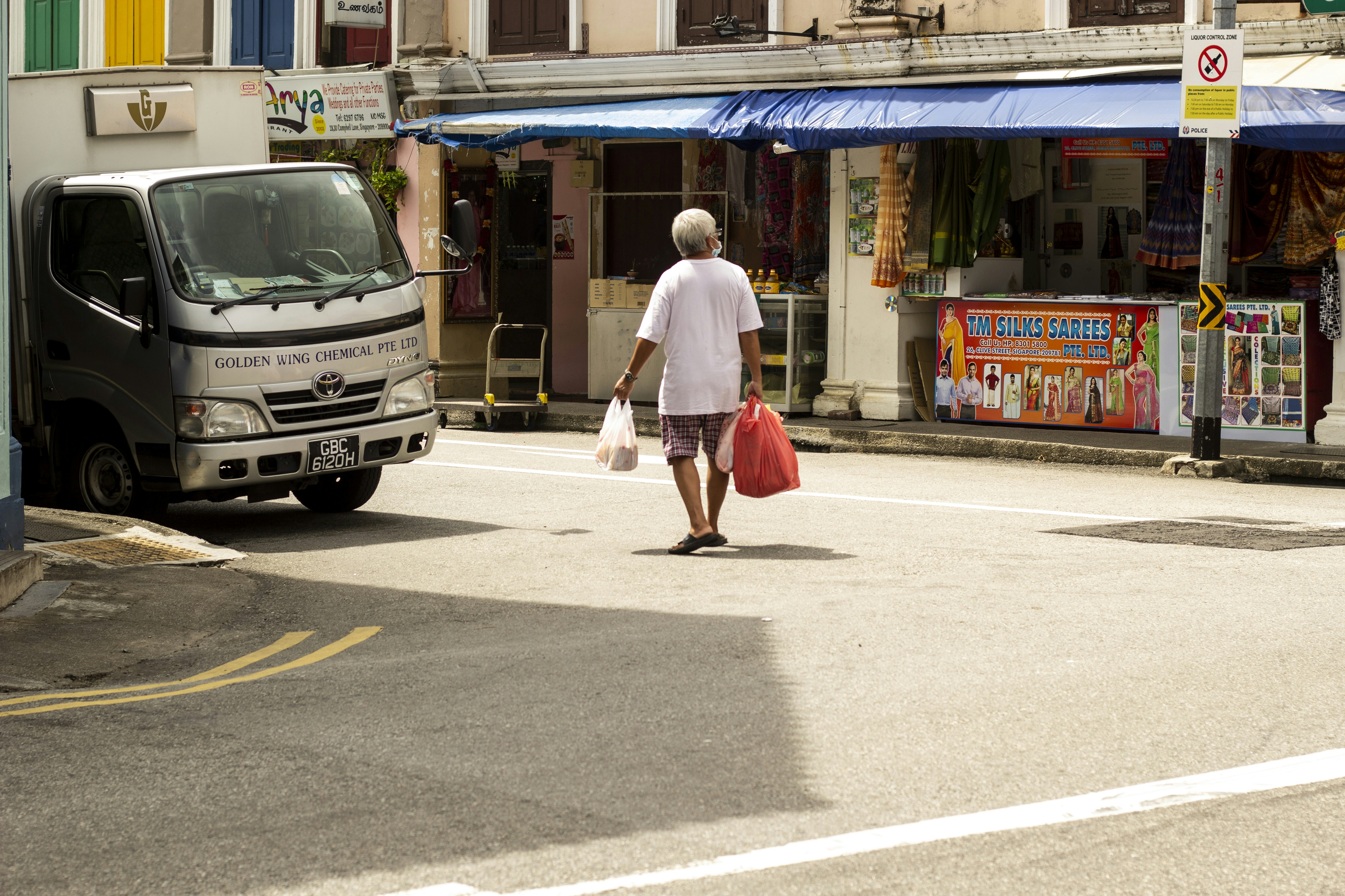 man in white t-shirt and red shorts walking on sidewalk during daytime