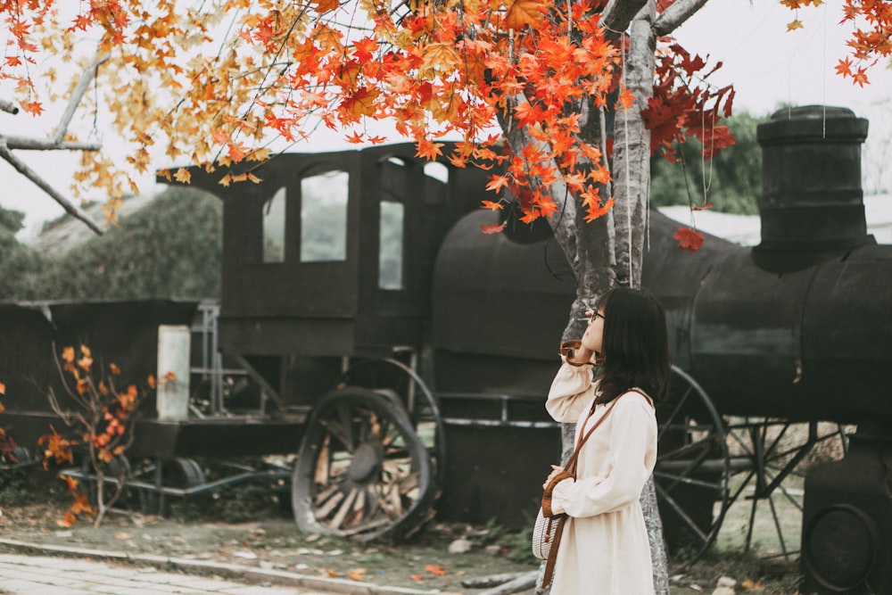 woman in white dress standing beside black wooden cart during daytime