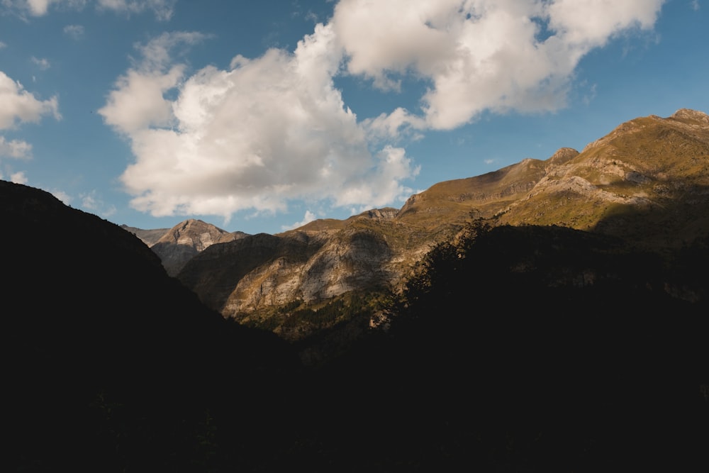 brown and green mountain under white clouds and blue sky during daytime