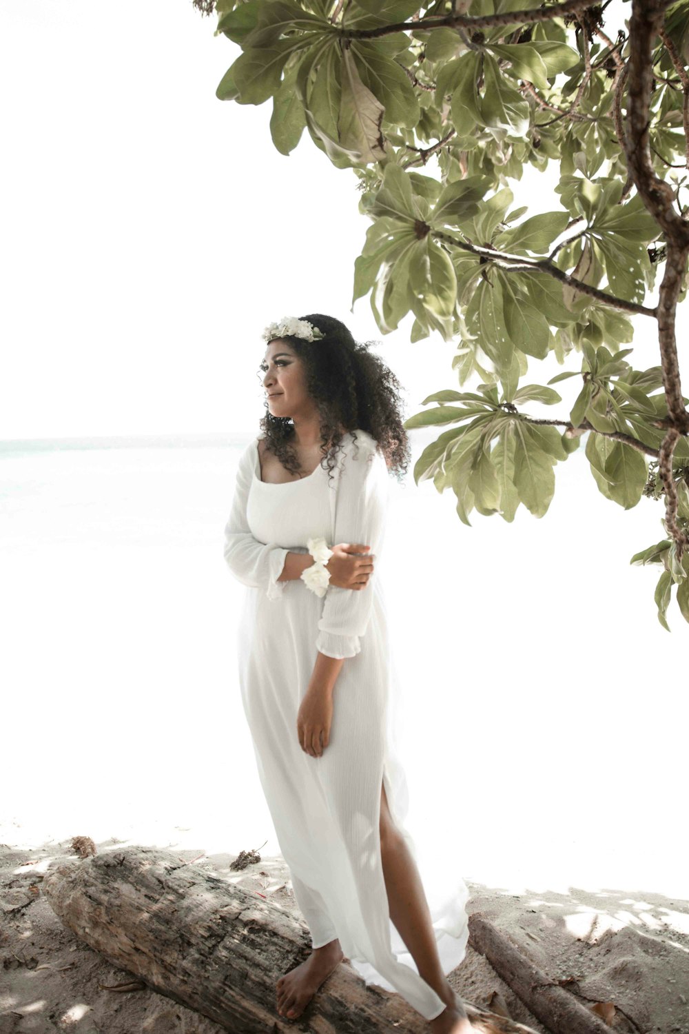 woman in white dress standing under green tree