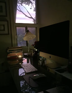 A serene workspace with soft ivory tones, gold accents, candles gently glowing, and a laptop open to a video course.