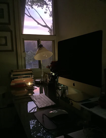 A serene workspace with soft ivory tones, gold accents, candles gently glowing, and a laptop open to a video course.