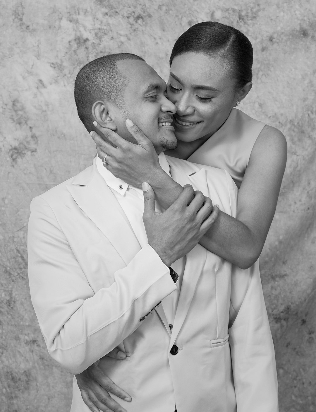 man in white dress shirt hugging woman in white sleeveless dress