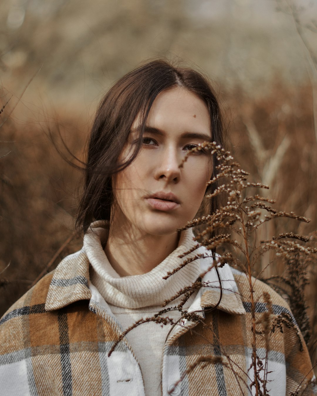 woman in white and brown sweater standing on brown grass field during daytime