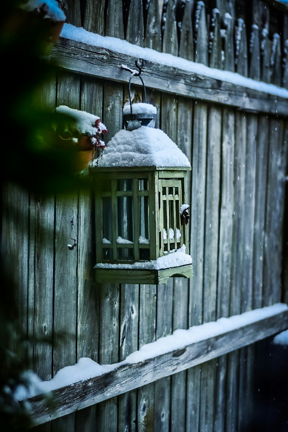 a bird feeder hanging from the side of a wooden fence