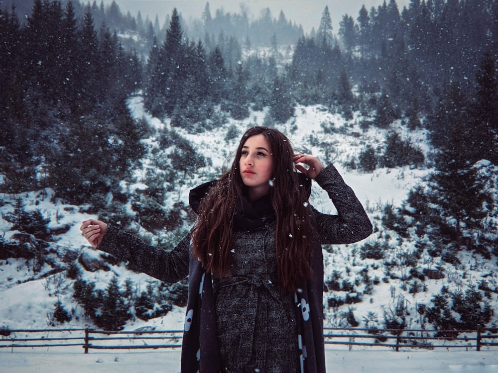woman in black and gray plaid coat standing on snow covered ground