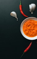 soup in white ceramic bowl beside red handled spoon and fork on black table