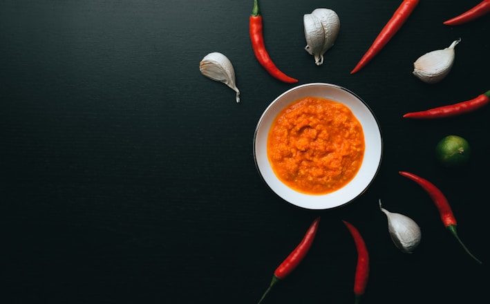 soup in white ceramic bowl beside red handled spoon and fork on black table