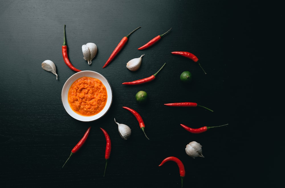 red chili pepper and green chili on white ceramic bowl