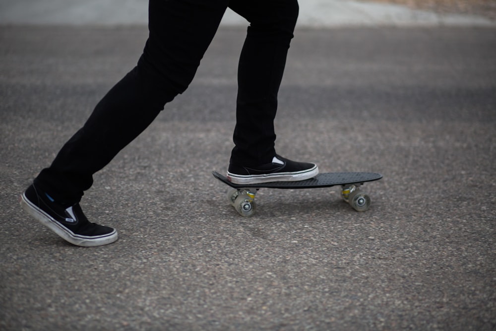 person in black pants and black shoes standing on skateboard during daytime