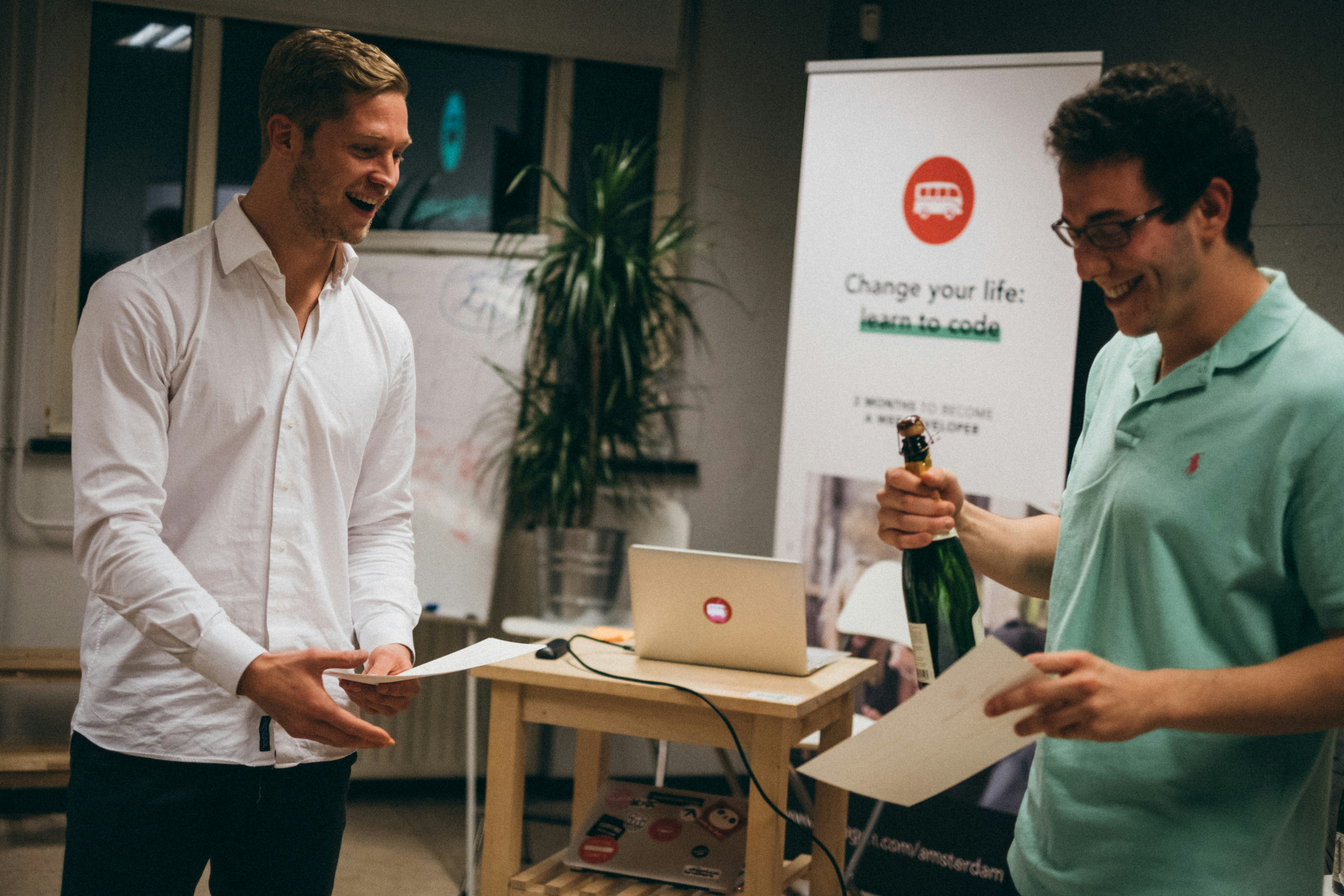 man in white dress shirt holding green bottle diploma teams background