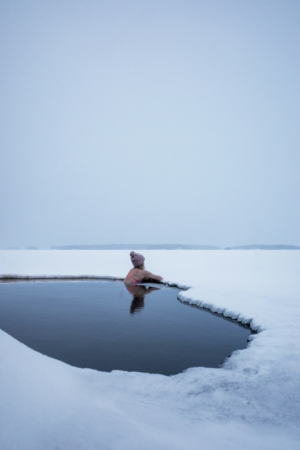 man in red shirt and black pants sitting on snow covered ground during daytime