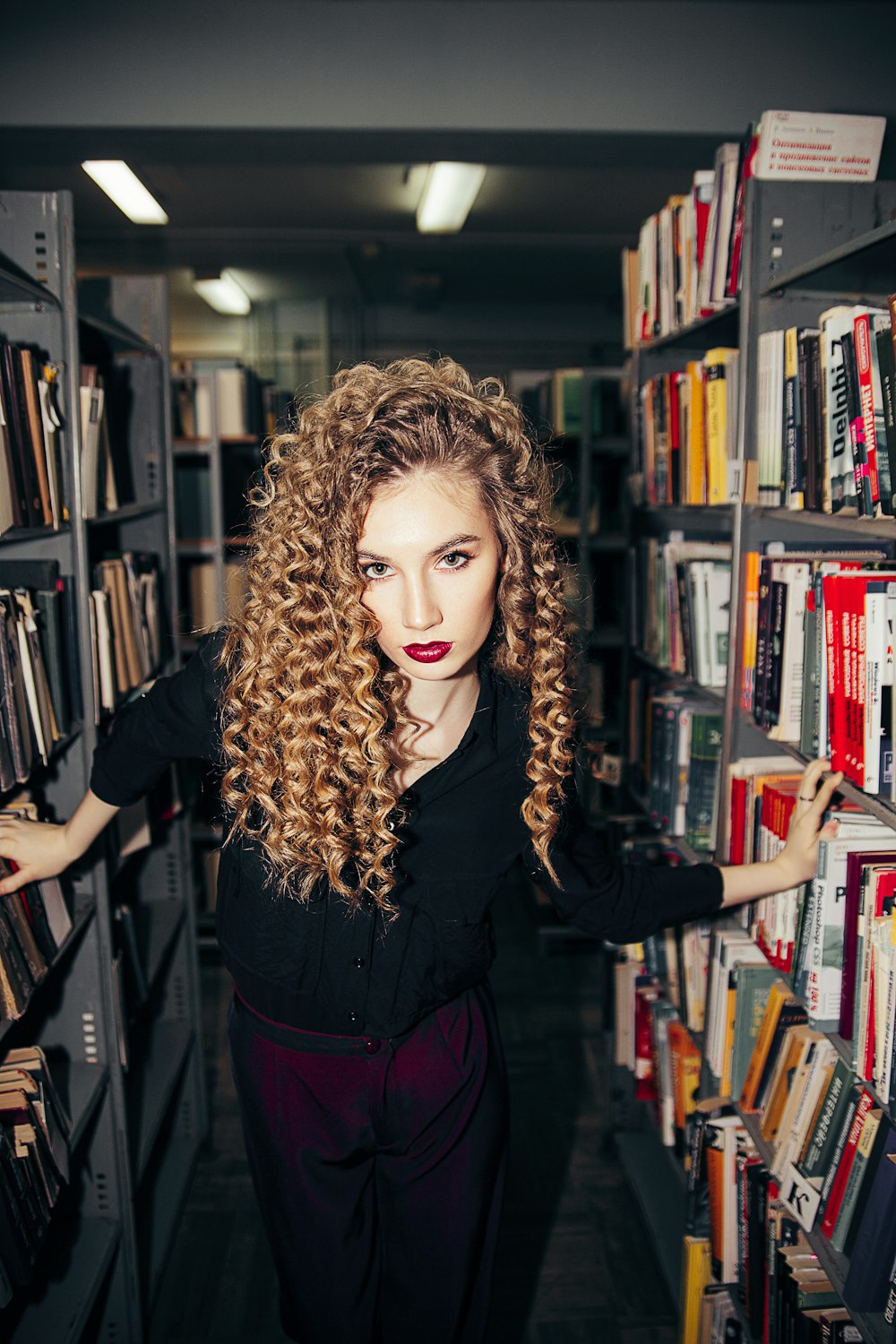 woman in black long sleeve shirt standing near books