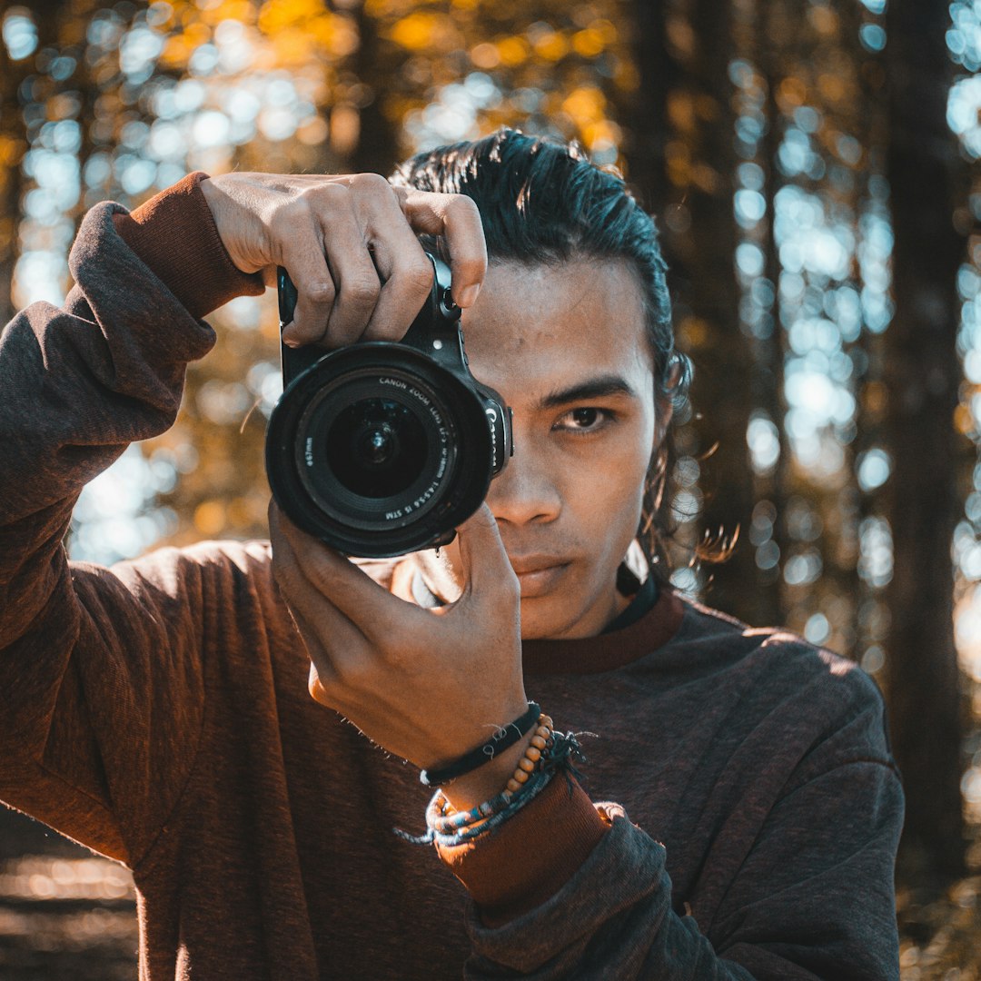 man in brown long sleeve shirt holding black camera