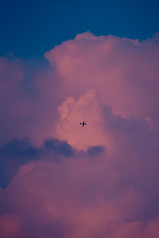 A sleek airplane soaring above fluffy clouds at sunset, symbolizing the start of an unforgettable journey.