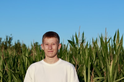 Lalit Singh standing proudly in front of the lncg farm's lush cornfields under a bright sky.