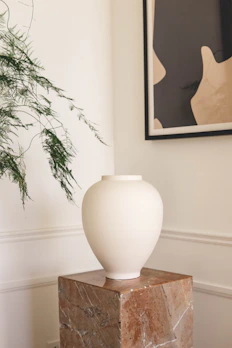 An elegant marble vase with subtle veining, placed on a polished wooden console.