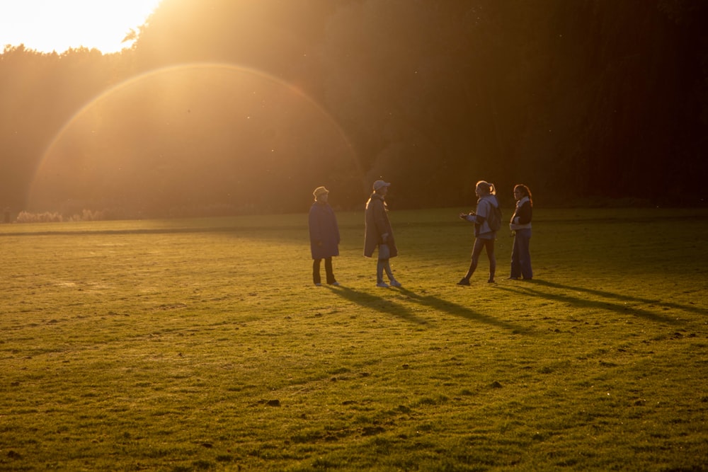 3 person walking on green grass field during daytime