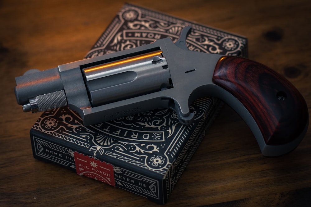 silver and brown revolver pistol on black and white book