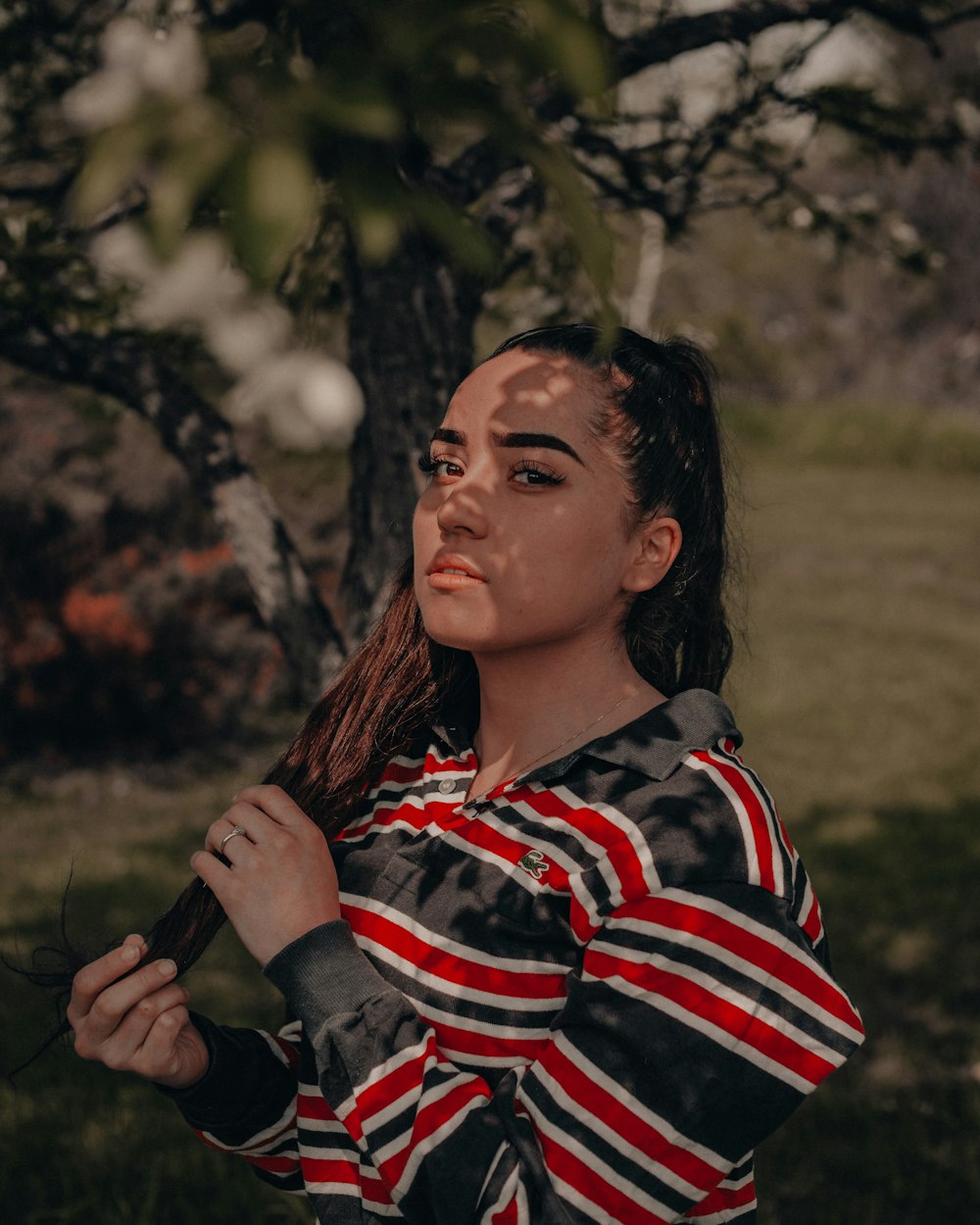 woman in black white and red striped shirt standing on green grass field during daytime