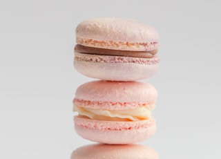 Three delicate French macarons stand on top of each other with a pink ribbon on a white background. Vintage. Advertising. Desser. Postcard. Place for an inscription. View from above. Dessert with tea.