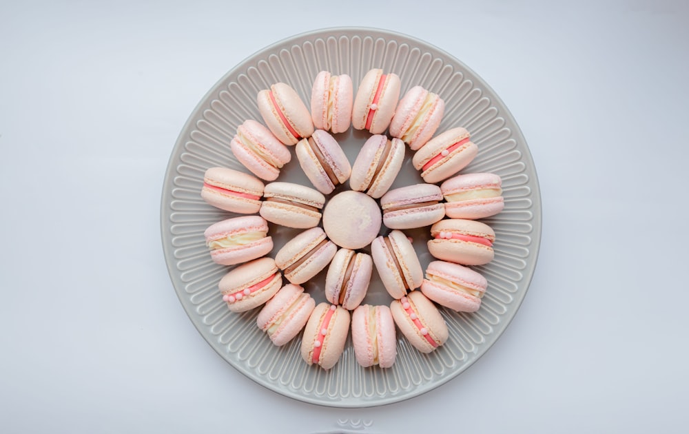 a plate of pink and white macaroons on a white table