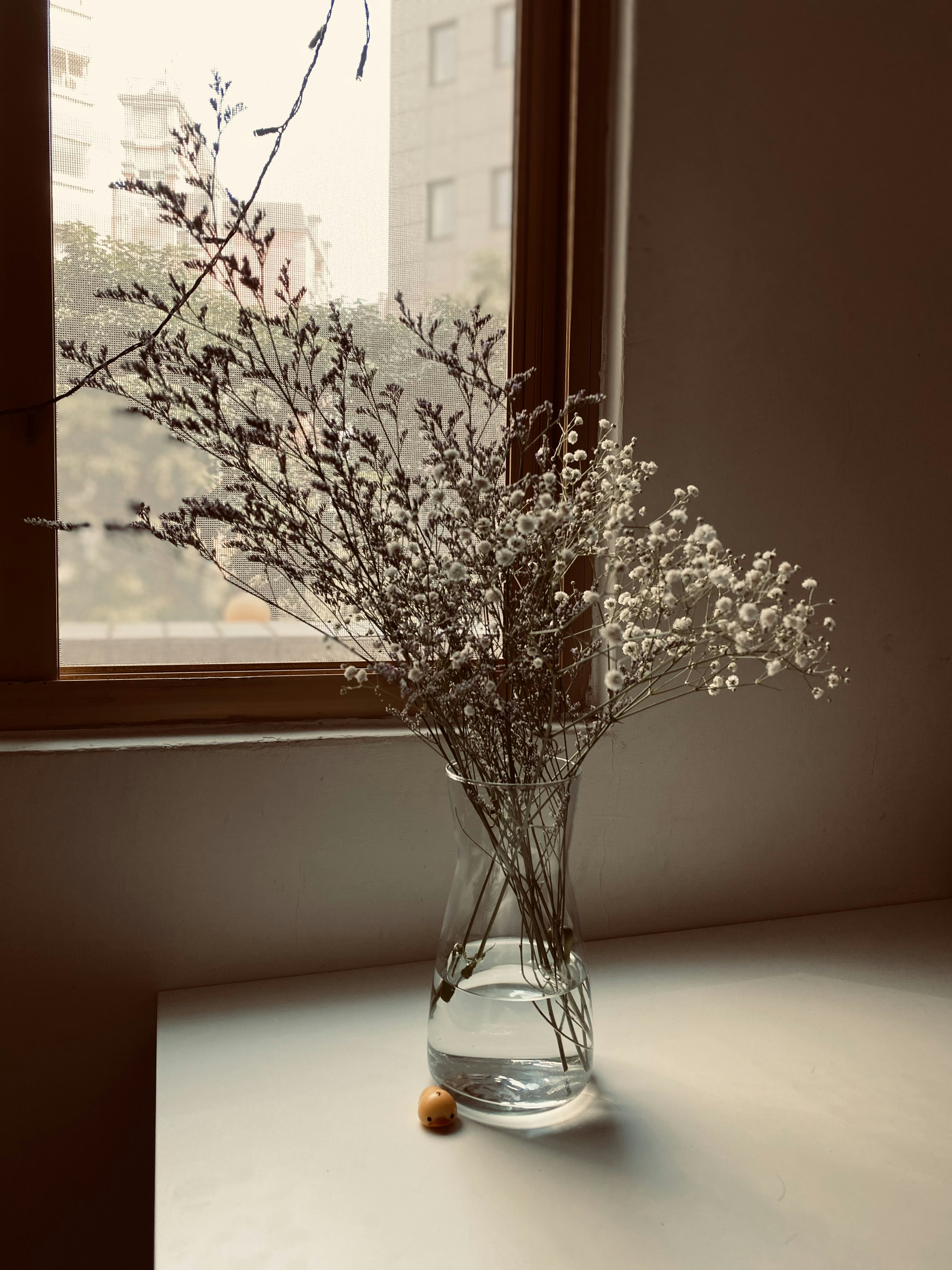 Small colorful flower figurine on a sunny windowsill with warm natural light streaming in