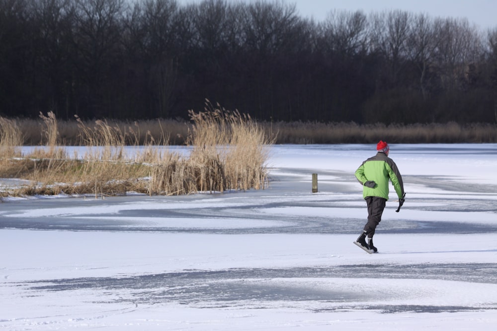 man in green jacket and black pants walking on snow covered ground during daytime