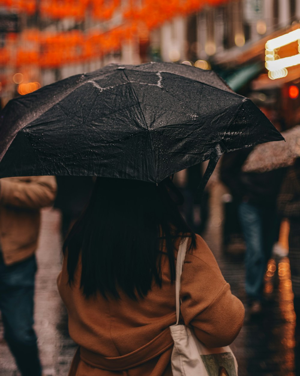 傘を持つ茶色のコートの女性