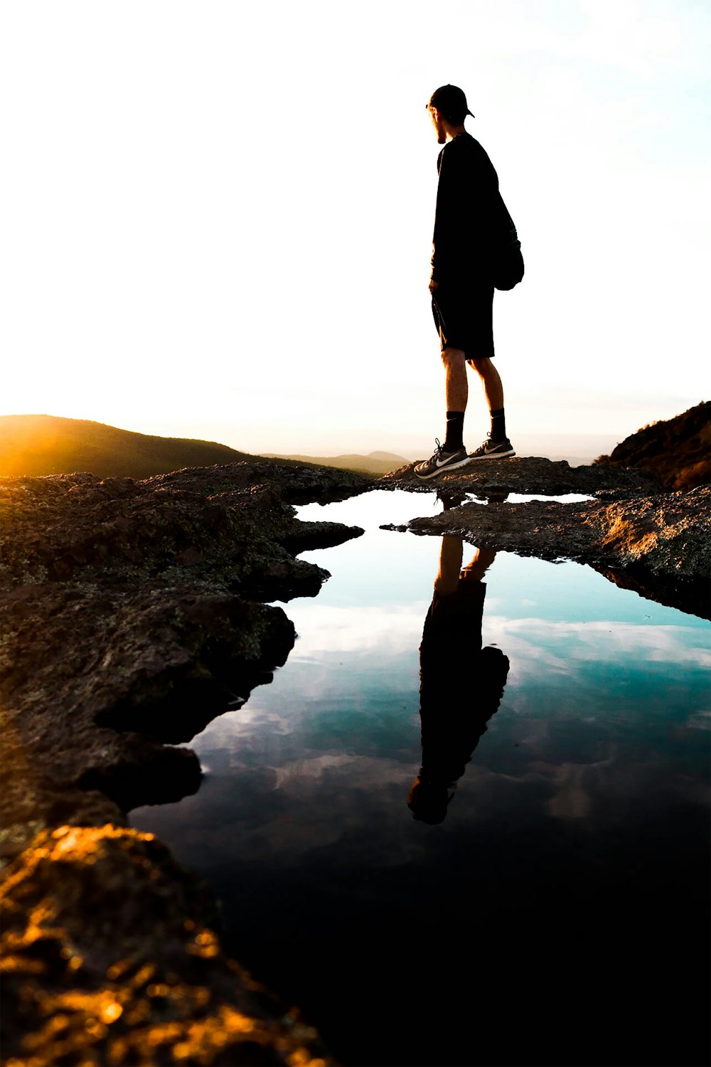 silhouette of person standing on rock formation during sunset