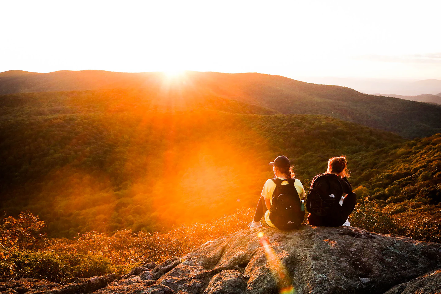 Two friends on a rock at sunset