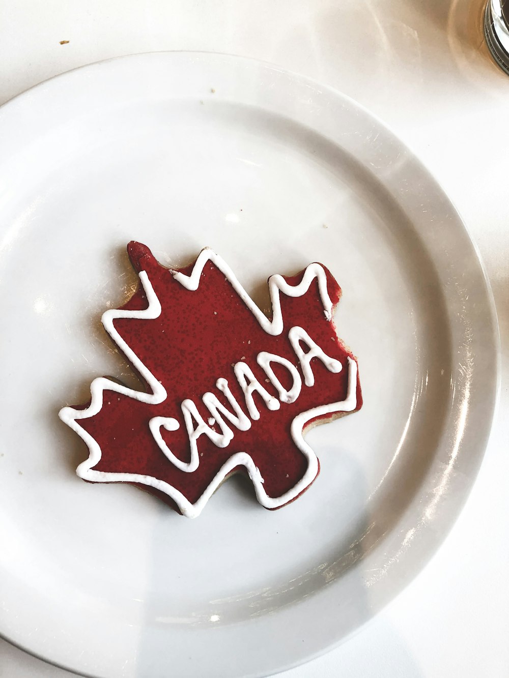a white plate topped with a cookie shaped like a maple leaf