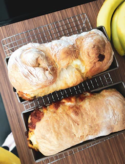 Amber’s hands gently placing freshly baked mini banana bread loaves on a cooling rack