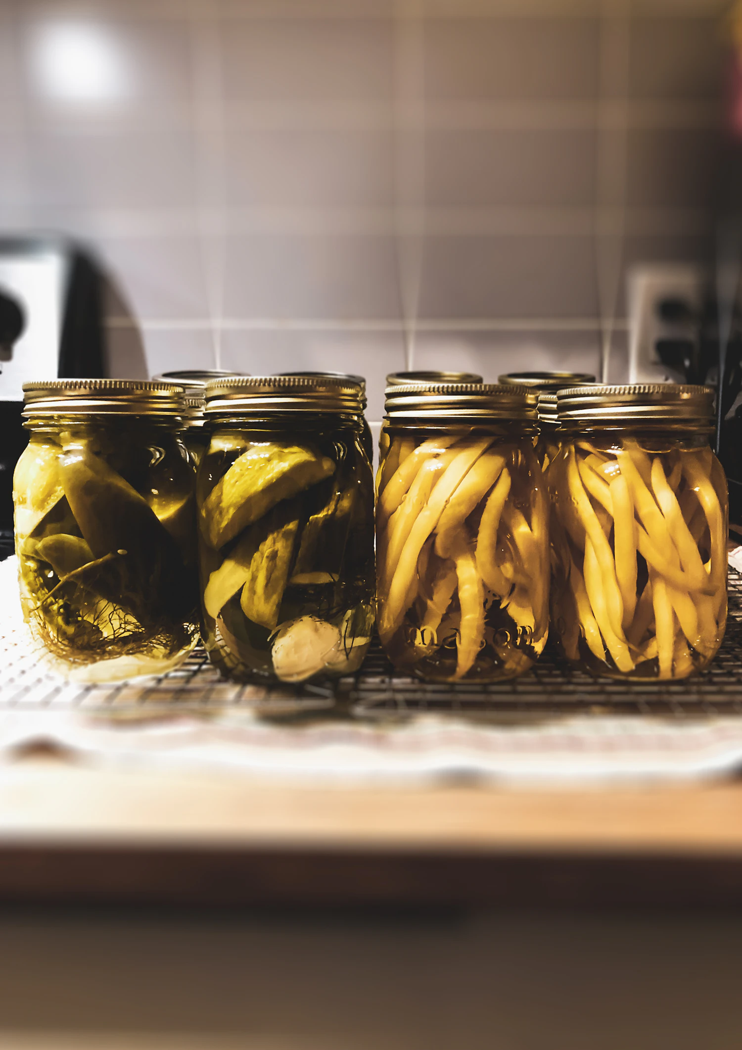 Jars of dilled beans and cucumbers on a wire rack