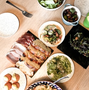 sliced meat on white ceramic plate beside green vegetable salad on white ceramic bowl