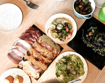 sliced meat on white ceramic plate beside green vegetable salad on white ceramic bowl