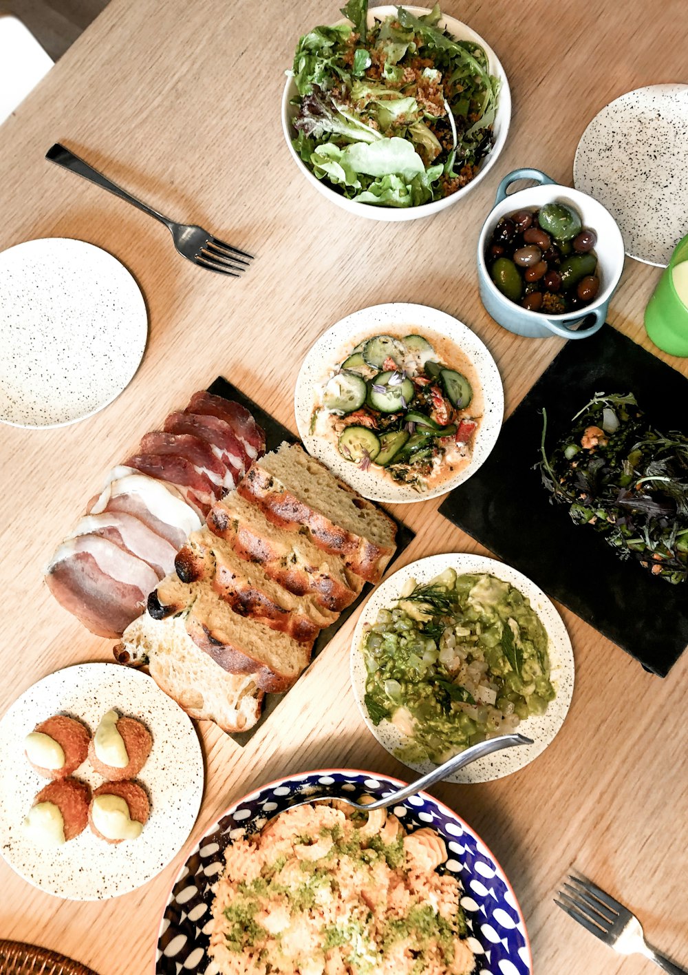 sliced meat on white ceramic plate beside green vegetable salad on white ceramic bowl