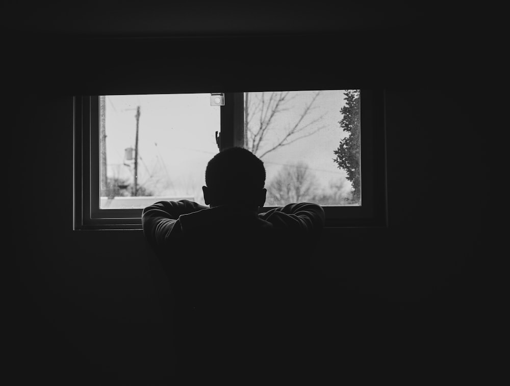 man in black and white stripe long sleeve shirt sitting on chair looking at the window