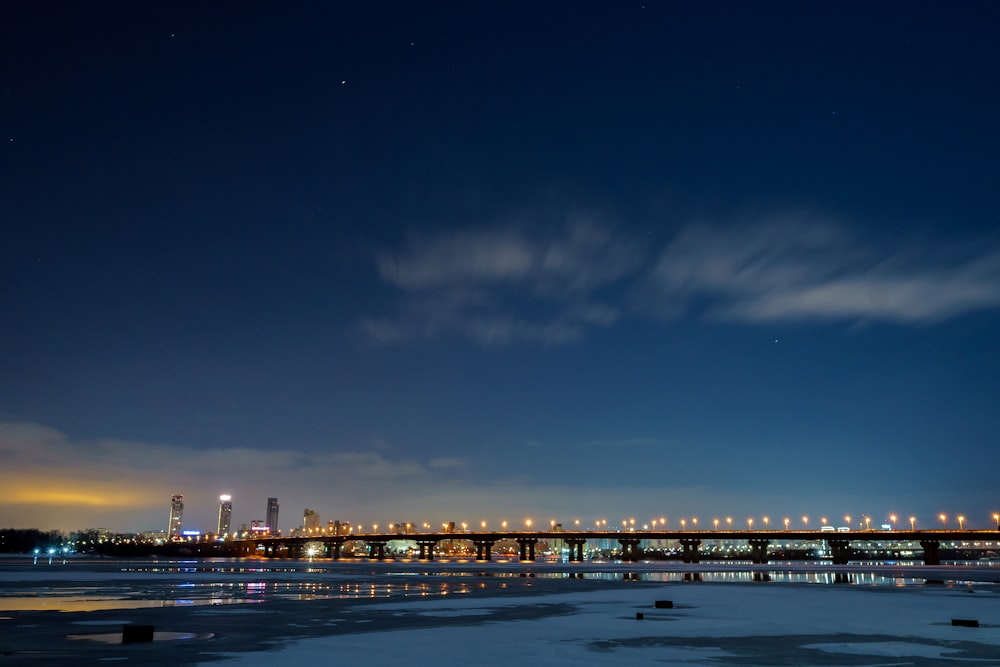 city skyline across body of water during night time