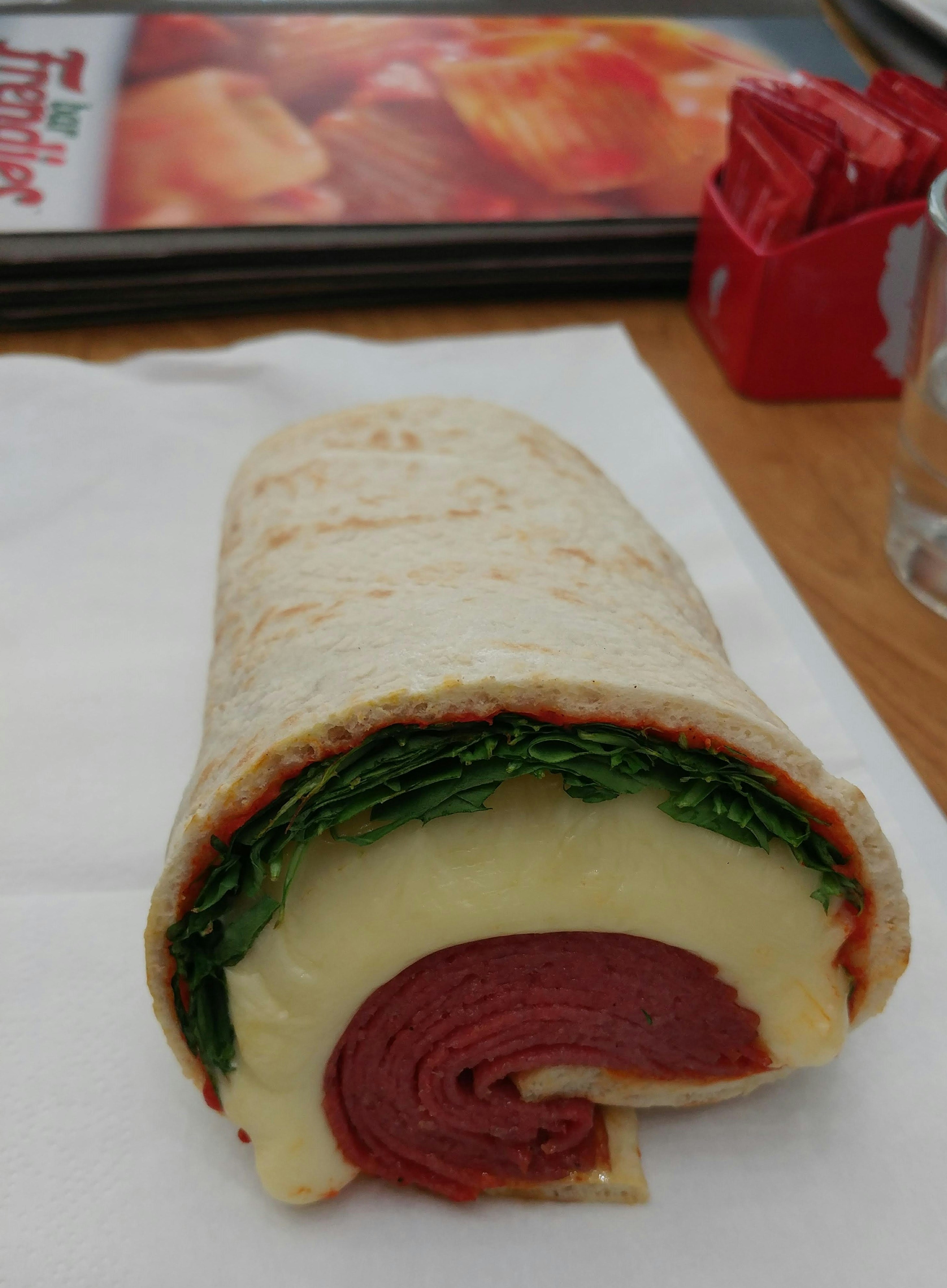 Egg white omelette wrap with spinach and mushroom filling on a wooden cutting board