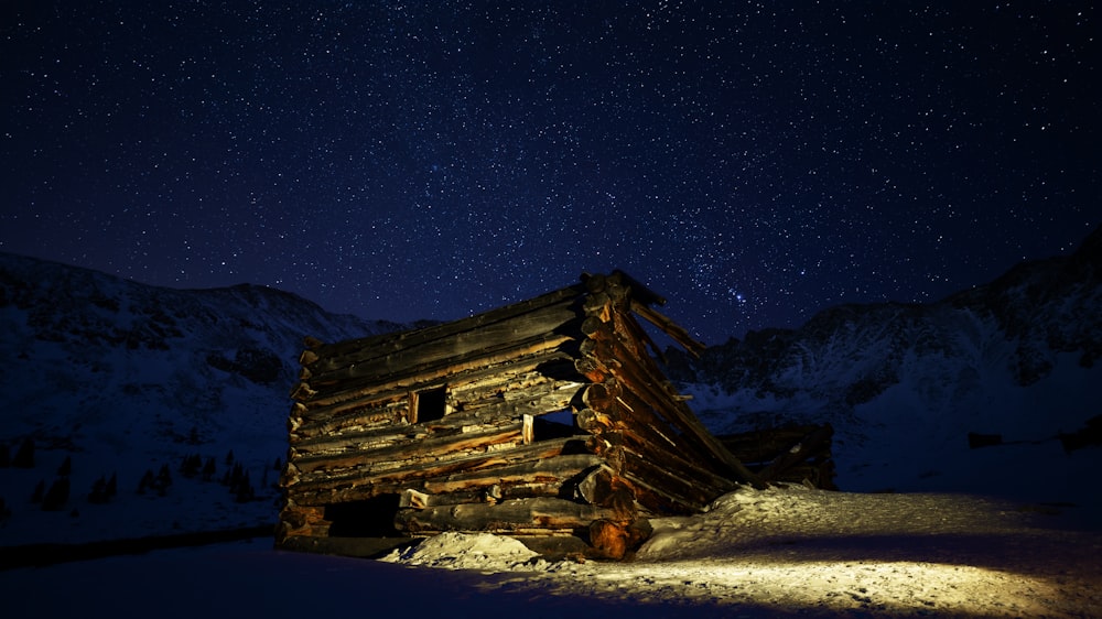 Casa de madera marrón en suelo cubierto de nieve durante la noche