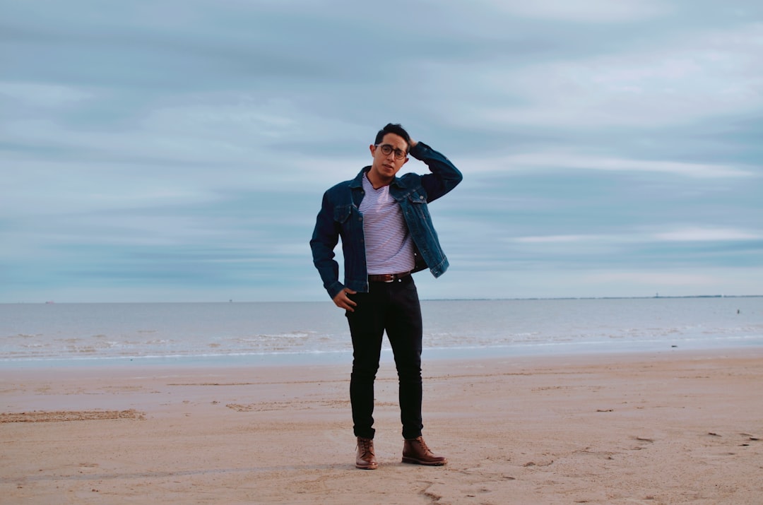 man in gray jacket standing on beach during daytime
