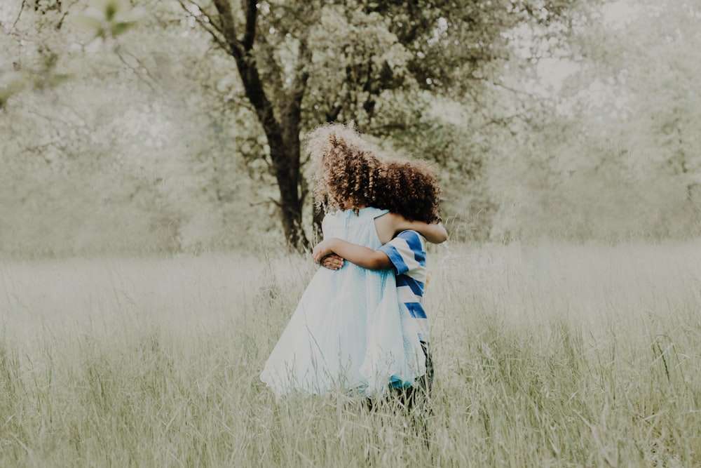 girl in white and blue dress standing on green grass field during daytime