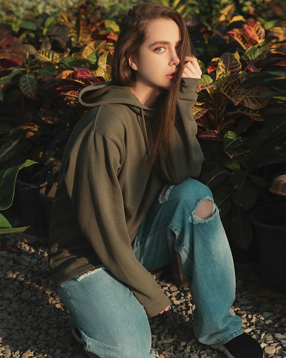 woman in brown coat and blue denim jeans sitting on ground