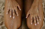 Close-up of intertwined hands resting on soft sand, bathed in warm afternoon sun.