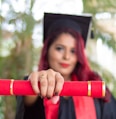 woman in red long sleeve shirt holding red and black academic hat