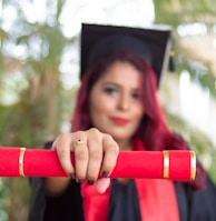 woman in red long sleeve shirt holding red and black academic hat