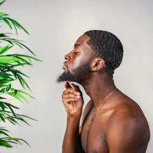 Male influencer applying beard oil during a natural, candid grooming routine outdoors.
